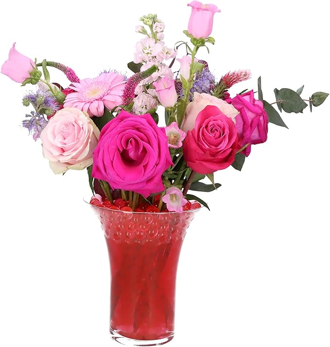 Composizione di rose rosa e fucsia in un vaso di vetro decorato con perle d'acqua rosse